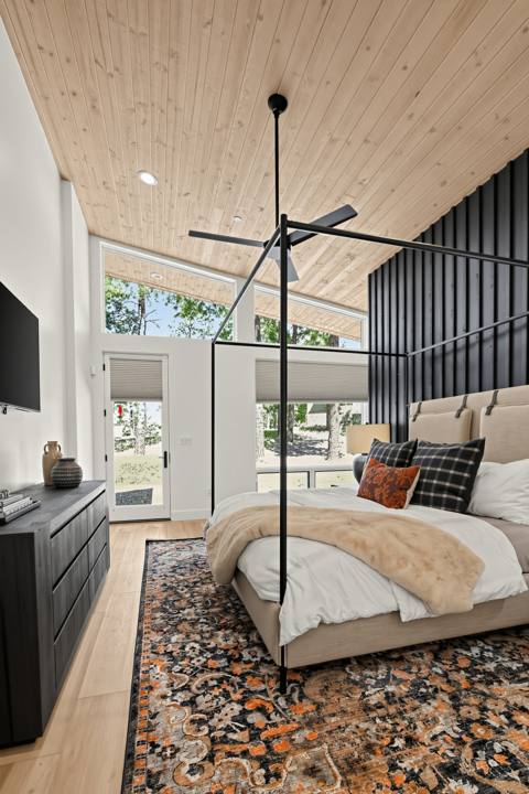 Primary bedroom with wood ceiling, canopy king bed and patio door