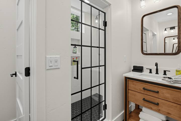 Bathroom with black grid glass shower and wood vanity