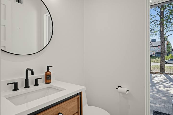 Powder room with round mirror and wood vanity