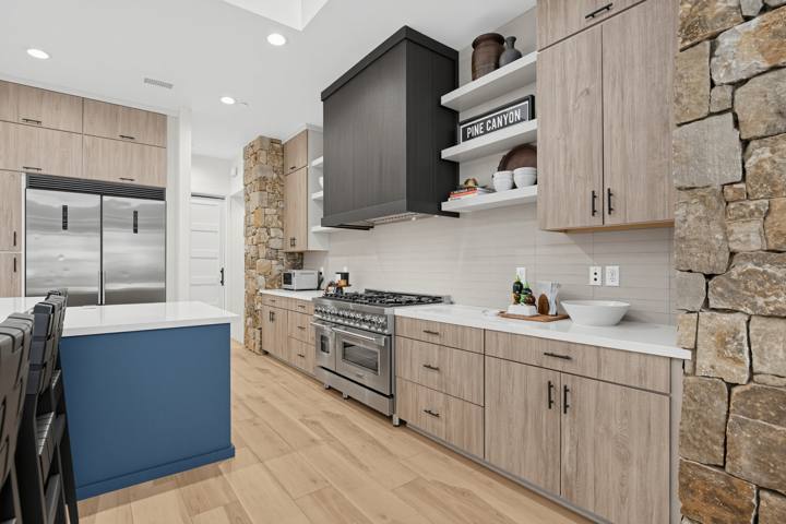 Kitchen with blue island, gas range and stone column